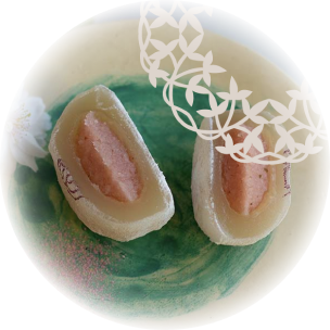 Deux demi-mochis sur une assiette décorée, exposant une garniture rose de framboise douce, contrastant avec la blancheur de la pâte de riz externe.