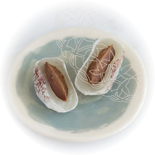 Mochi coupé en deux, montrant une farce marron foncé de haricot rouge aromatisée au thé hojicha, présenté sur une assiette en céramique bleu pastel.