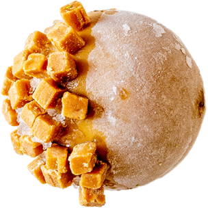 Mochi au caramel avec des morceaux de caramel doré sur le dessus, saupoudré de poudre de cacao, sur un fond noir.